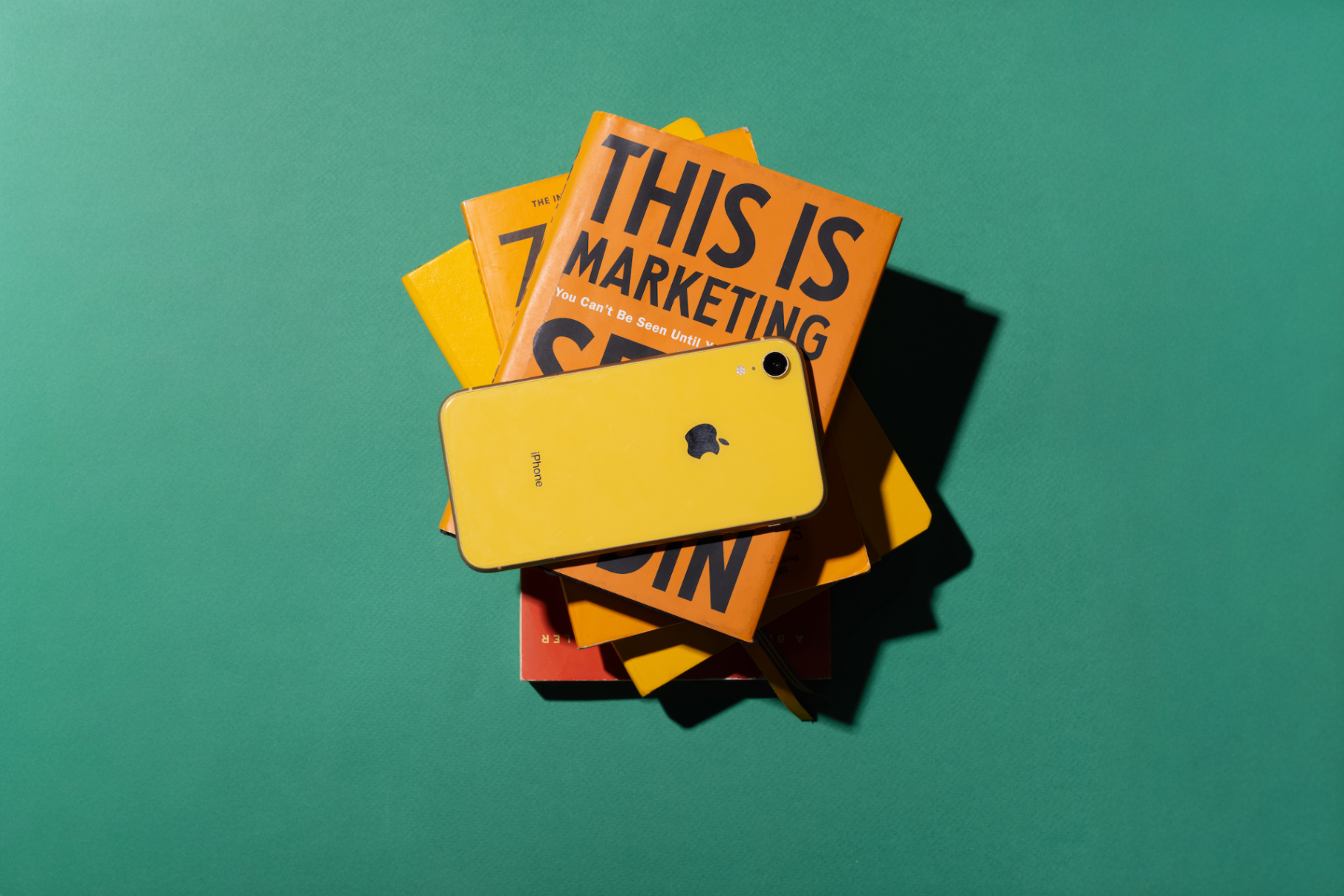 Marketing books including 'This Is Marketing' by Seth Godin stacked with an iPhone, the modern marketer's toolkit for digital marketing strategy